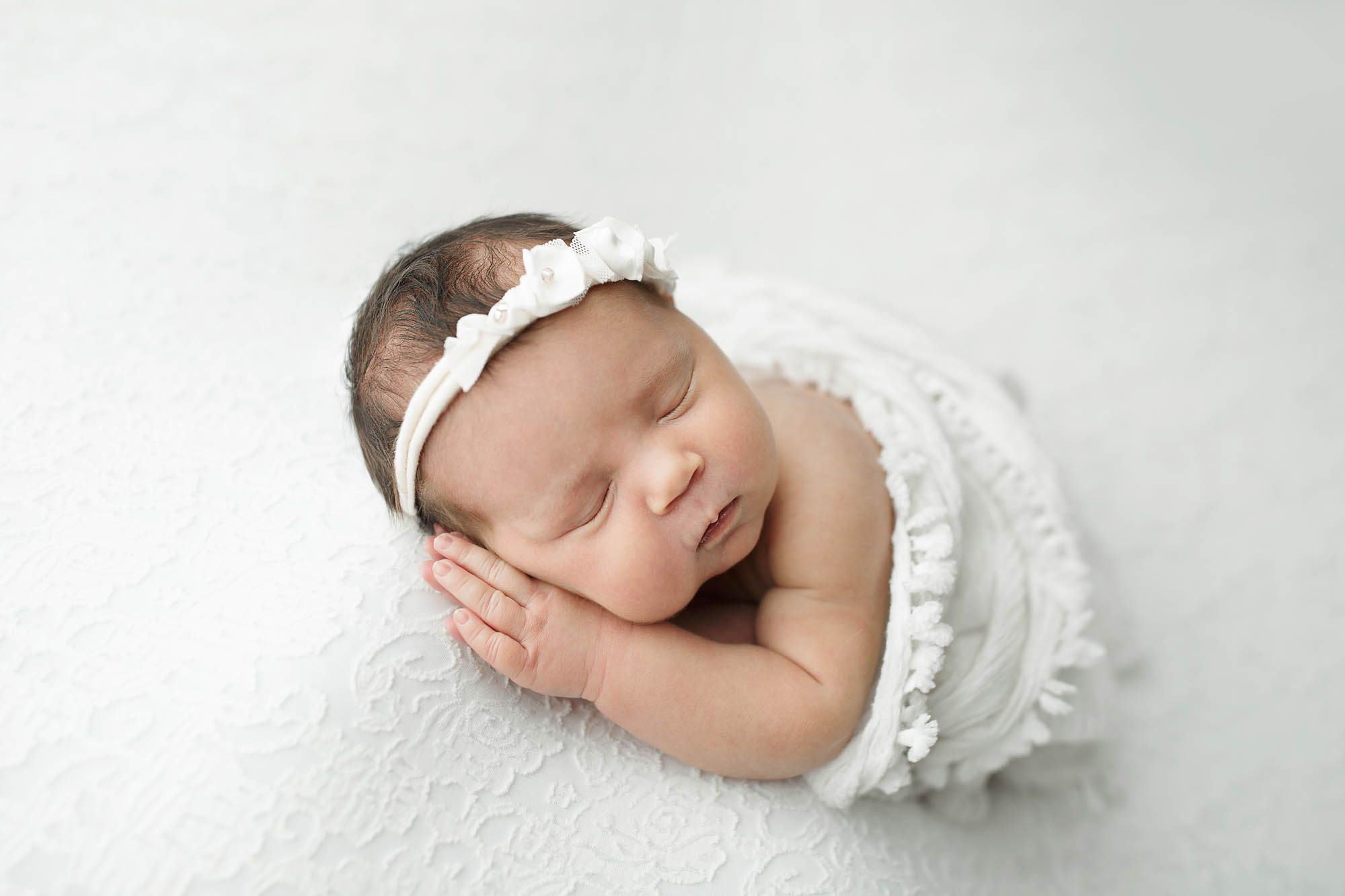 Canton Newborn Photographer Saren Cassotto newborn girl photo in a white ruffled wrap and a white ruffled headband